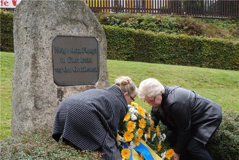 Beim 60. Umsiedlungstag legen die Ratsdamen Shirly Beck und Karin Schwarz einen Kranz am Denkmal nieder.