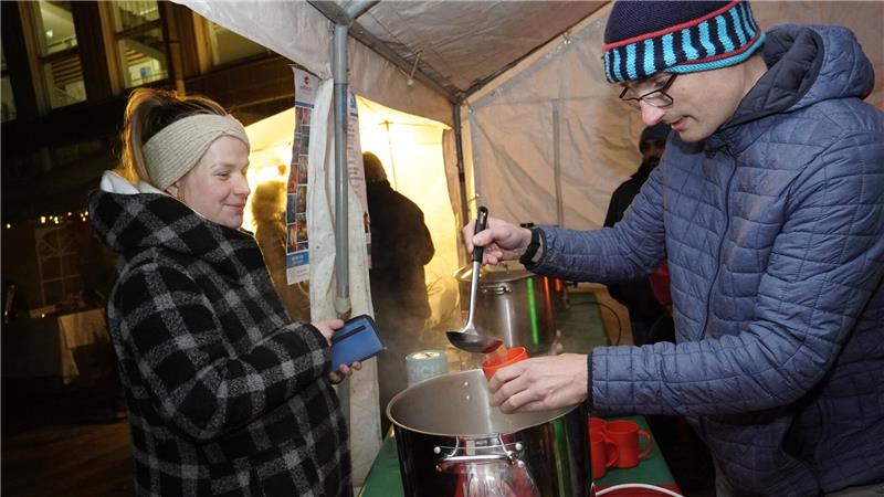 Ein Mann schenkt einer Frau Glühwein aus.