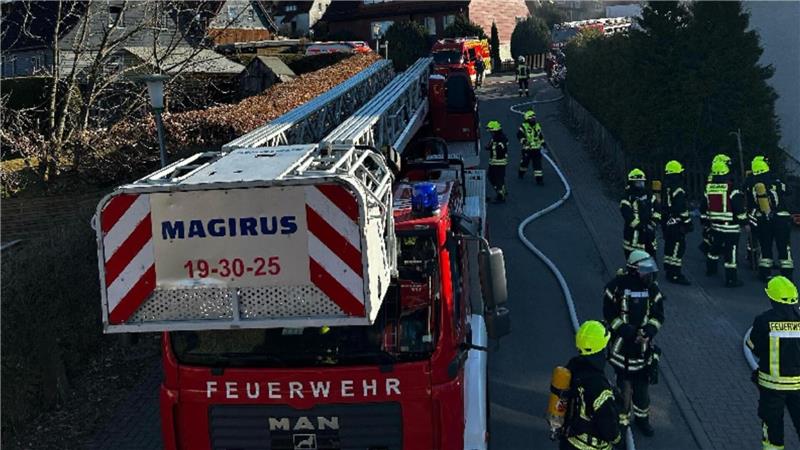 Ein Feuerwehreinsatz. Im Vordergrund ein Drehleiterfahrzeug und Einsatzkräfte. 