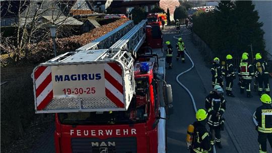 Ein Feuerwehreinsatz. Im Vordergrund ein Drehleiterfahrzeug und Einsatzkräfte. 