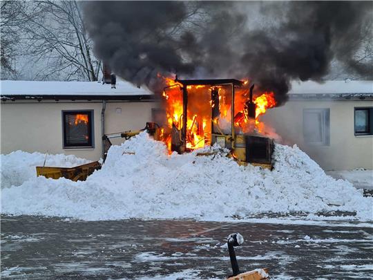 Beim Eintreffen der Feuerwehr schlagen Flammen aus dem Radlader. Eine private Räumfirma hatte das brennende Fahrzeug vorsorglich in einen Schneeberg gehüllt. Foto: Feuerwehr Seesen