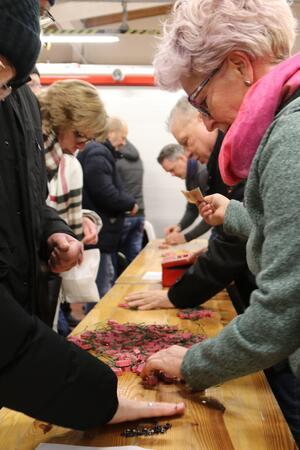 Der GZ-Schweinchenverkauf läuft in Goslar auf Hochtouren Mehrere Personen stehen an einem langen Holztisch und legen kleine rote und schwarze Gegenstände darauf