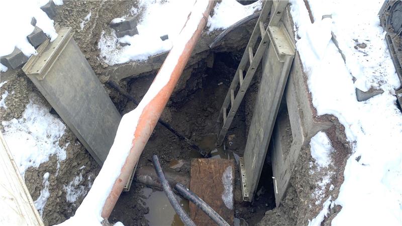 Kanalschaden bei Glasfaserarbeiten in Schladen Baugrube mit Leiter, Betonwand und Schnee am Rand.