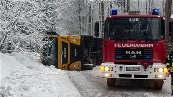 Das Foto zeigt einen Feuerwehrwagen vor einem umgekippten Lkw.