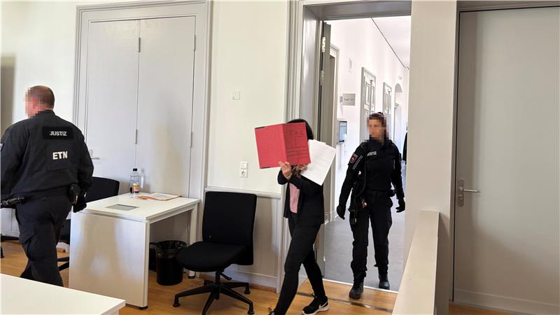 Die Angeklagte verbirgt ihr Gesicht mit einem Ordner.