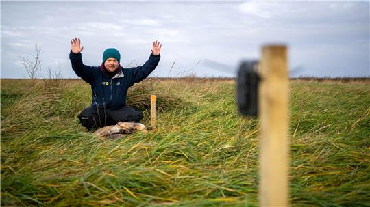 Benedikt Wiggering testet eine Wildtierkamera, die andere Tiere an einem toten, ausgelegten Reh in den Salzwiesen dokumentieren soll.