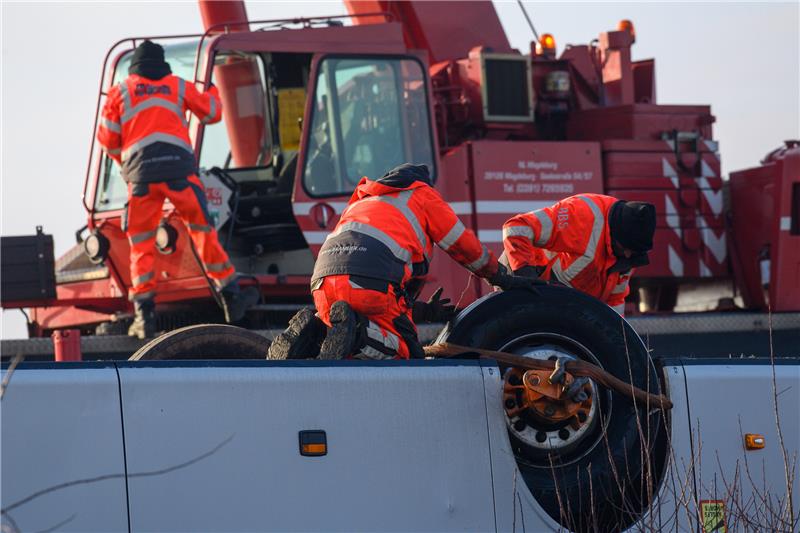 Irxleben: 35 Verletzte bei Busunglück auf A2 Bergungsarbeiter befestigen die Achse von einem Bus der neben der Fahrbahn der Autobahn A2 auf dem Dach liegt an einem Kran. Foto: picture alliance/dpa | Klaus-Dietmar Gabbert