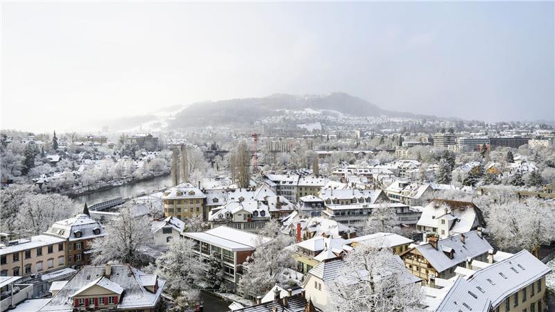 Bern im Winterkleid: Schnee auf Dächern und Bäumen, der Gurten taucht aus leichtem Nebel auf