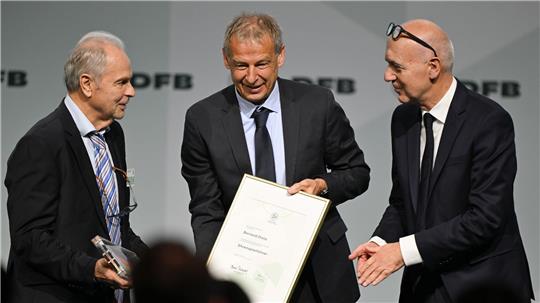 Bernard Dietz (l) wird von Jürgen Klinsmann und DFB-Präsident Bernd Neuendorf für die Ernennung zum Ehrenspielführer gratuliert.