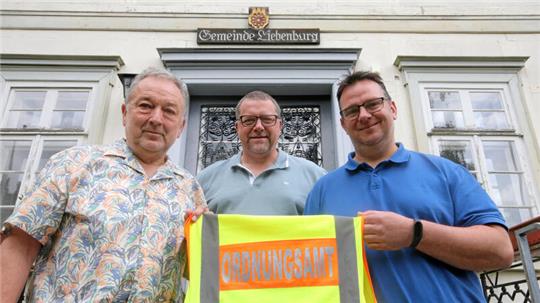 Bernd Rotzek (li.) reicht im Beisein von Bürgermeister Alf Hesse die Ordnungsamt-Weste an seinen Nachfolger Dennis Dorn (re.) weiter.