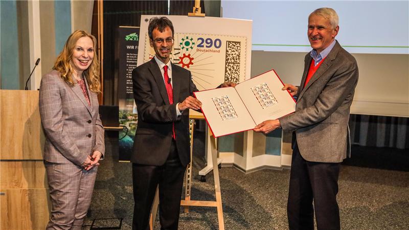 TU Clausthal und Bergschule feiern 250. Geburtstag Das Foto zeigt Mitarbeiter des Bundesfinanzministeriums, die ein Heft mit der Sonderbriefmarke zum 250. Geburtstag der TU Clausthal in der Aula Academica präsentieren.