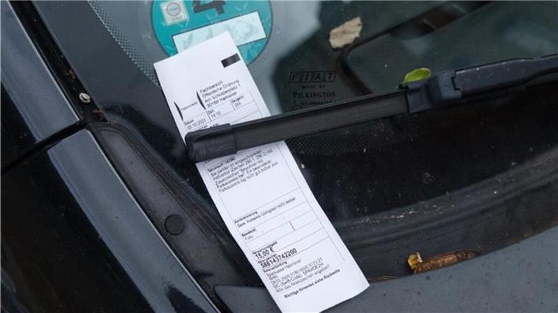 Windschutzscheibe eines Fahrzeugs mit einem unter dem Scheibenwischer eingeklemmten weißen Zettel