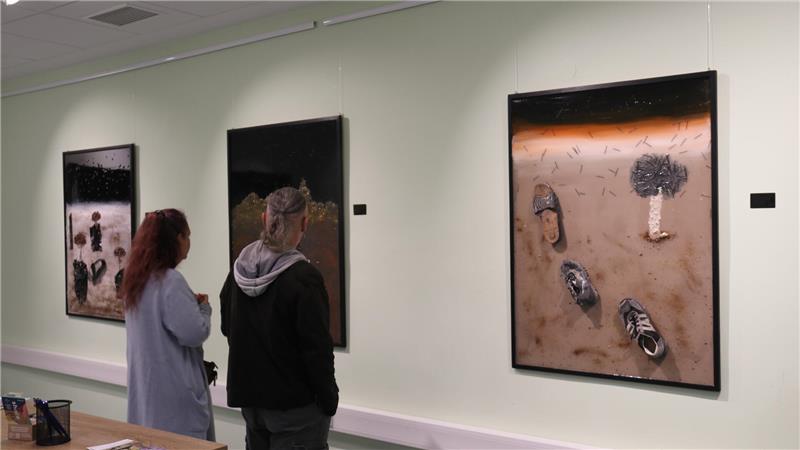 Besucher der Ausstellung „Verlassene Schuhe – bleibende Geschichte" im Mach-mit-Haus betrachten die Bilder von Qasim Alsharqy.