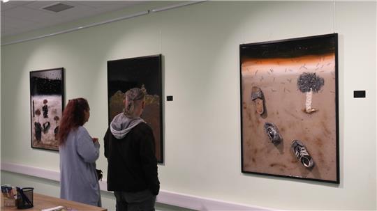 Besucher der Ausstellung „Verlassene Schuhe – bleibende Geschichte" im Mach-mit-Haus betrachten die Bilder von Qasim Alsharqy.