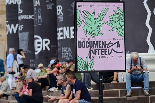 Besucher der documenta fifteen sitzen auf den Stufen des Fridericianums in Kassel.