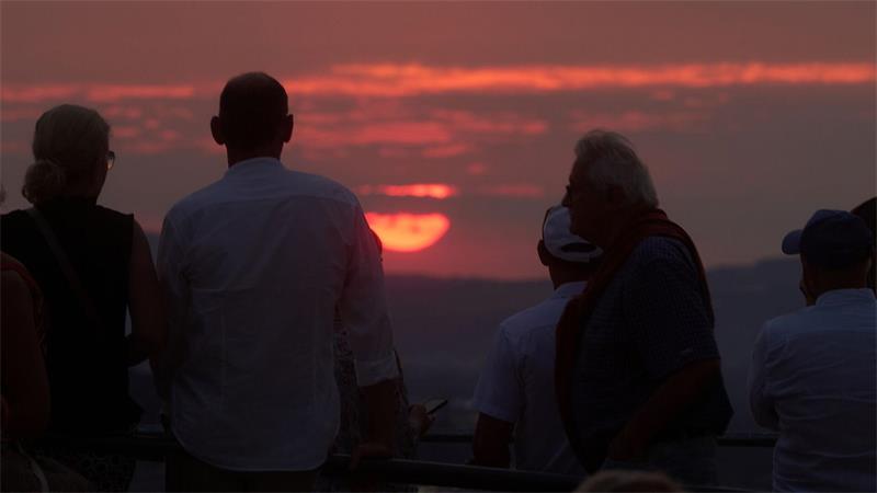 Besucher des Welt-Musikfestivals Horizonte in Koblenz schauen in einer Festivalpause von der Festung Ehrenbreitstein auf die untergehende Sonne.