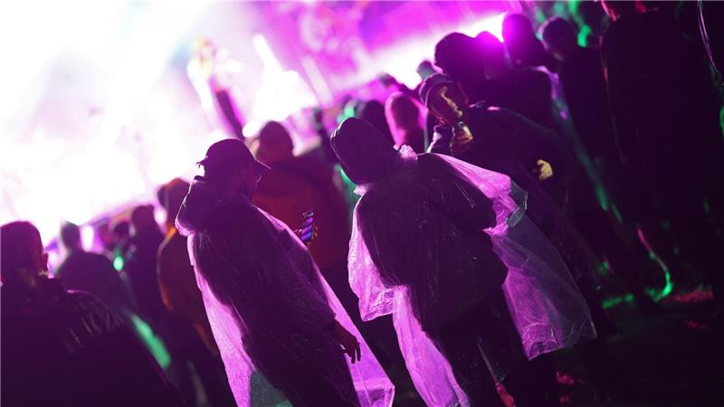 Besucher stehen am Abend mit Regenkleidung vor der Bühne des Festival Rocken am Brocken.
