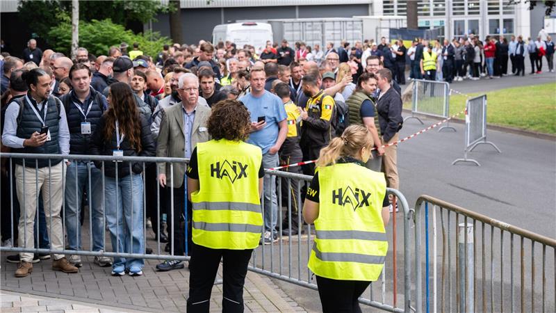 Besucher warten zu Messebeginn auf der Messe Interschutz vor der Halle 15.