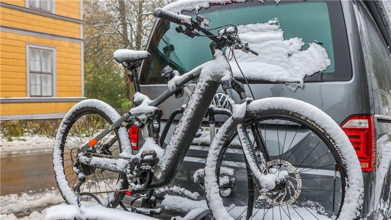 Ein schneebedecktes Mountainbike steht auf dem Fahrradanhänger eines Autos.