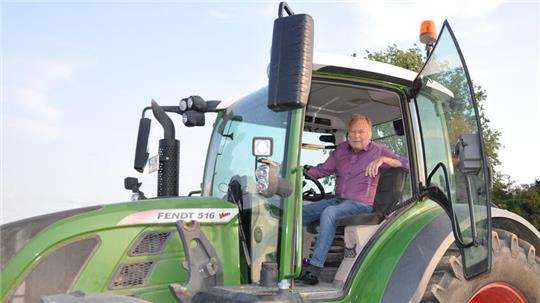 Ein Mann sitzt in der Fahrerkabine eines grünen Traktors vom Modell Fendt 516 mit geöffneter Tür.