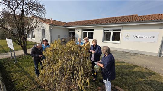 Birgit Gartner (r.), Leiterin der Tagespflege Vienenburg, schmückt mit Senioren und Mitarbeitern einen Busch auf dem Grundstück der Einrichtung mit Ostereiern.