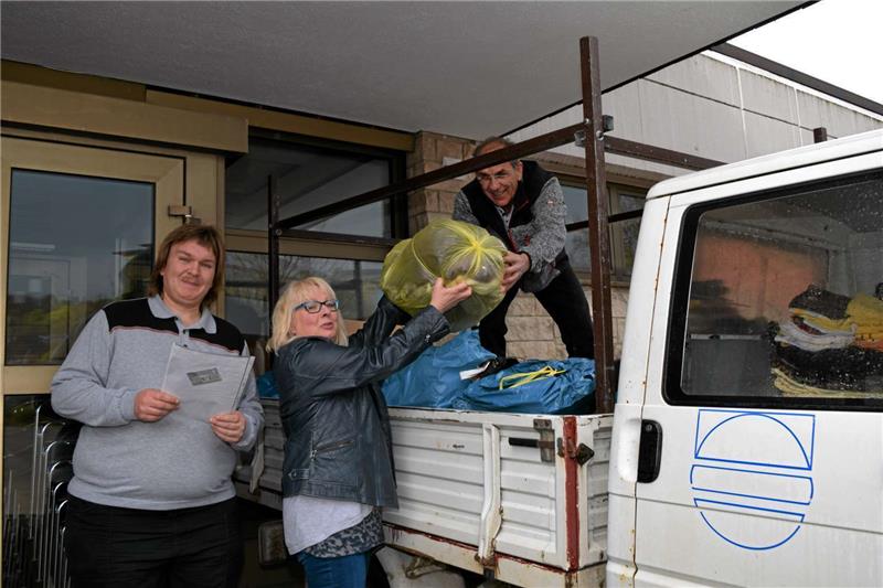 Birgit Nolte bringt in einer Arbeitspause Kleidung vorbei. Die laden Udo Reimann (rechts) und sein Freund Tobias Ulrich auf den Wagen. Fotos: Nöhr
