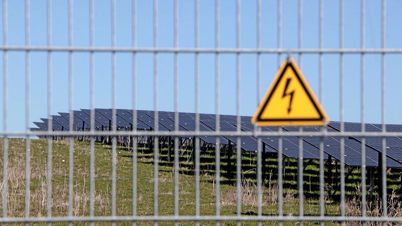 Hinter einem Metallzaun stehen die Module eines Solarparks.