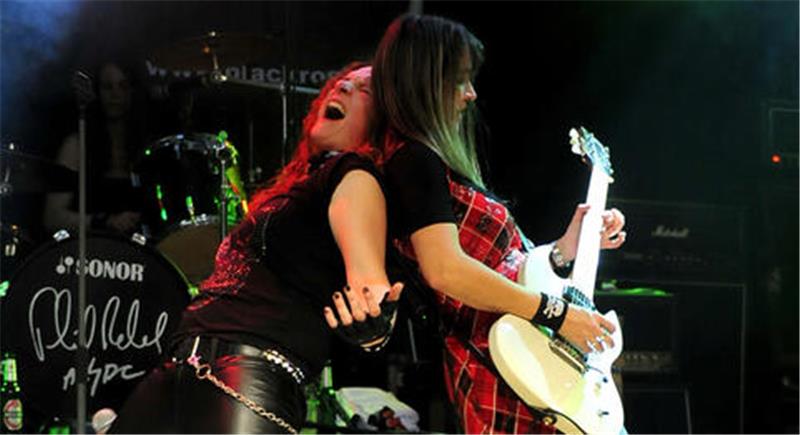 Zwei Musikerinnen rocken Rücken an Rücken auf der Bühne.