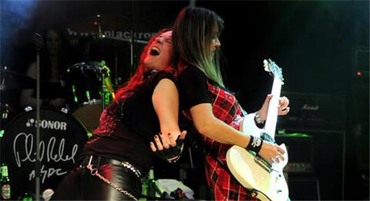 Zwei Musikerinnen rocken Rücken an Rücken auf der Bühne.