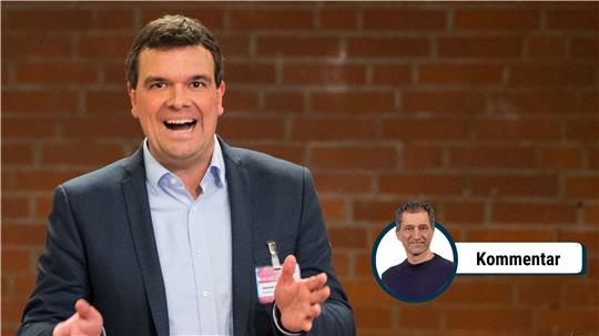 Ein Mann im grauen Anzug und im hellblauen Hemd mit offenem Mund.