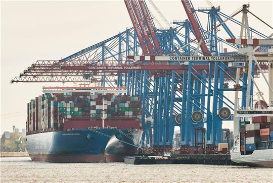 Blick auf Kräne und ein Containerschiff im Hamburger Hafen.