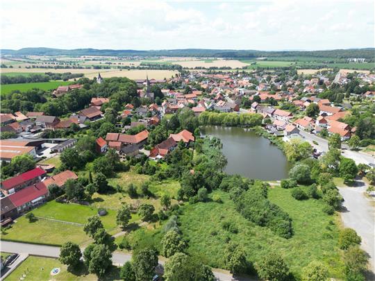 Blick auf Lutter aus der Vogelperspektive: In der Bildmitte befindet sich der Mühlenteich, die „grüne Hölle“ darunter ist die Schlammablagerfläche, die sich zu einem Biotop entwickelt hat. Rechts daneben ist der alte Festplatz zu sehen. Von dort aus wird das Biotop verkleinert. Foto: Neuendorf