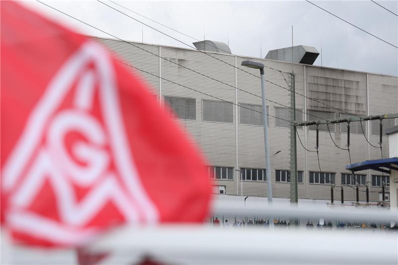 Die Fassade eines Unternehmens, davor weht eine Gewerkschaftsflagge.