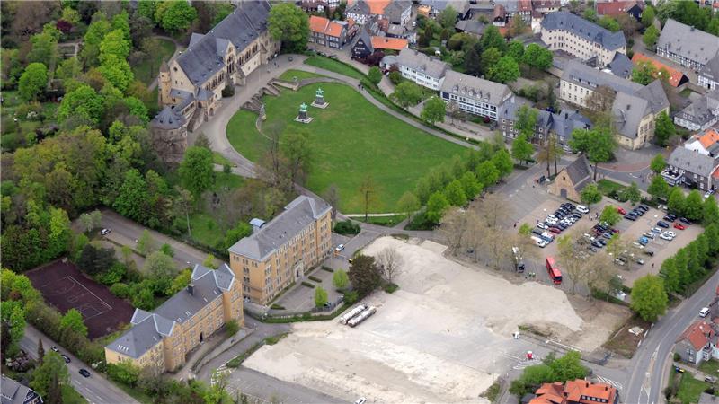 Luftaufnahme eines Parks mit mehreren historischen Gebäuden, einem großen Rasenplatz, Bäumen und einem angrenzenden Parkplatz