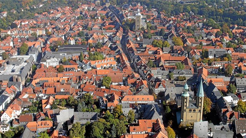 Luftaufnahme einer Stadt mit roten Dächern, einer langen Straße und mehreren Kirchtürmen