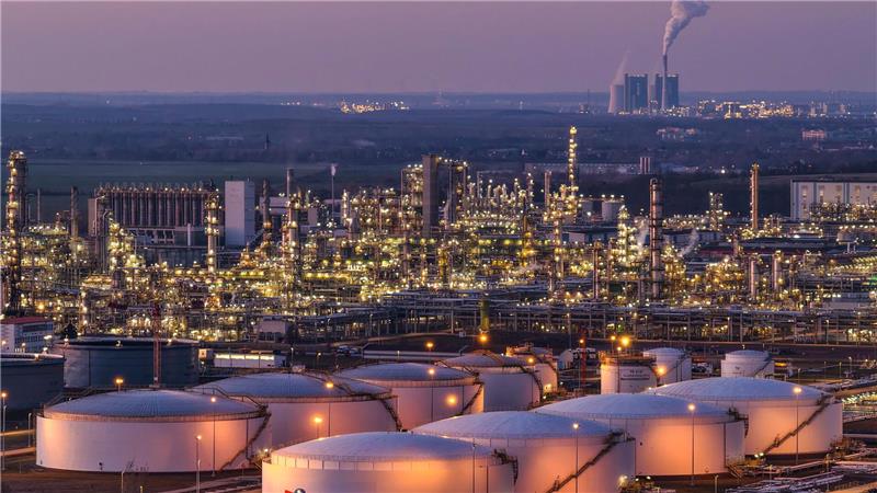 Blick auf die beleuchteten Anlagen der Total Energies Raffinerie im Chemiepark Leuna mit dem Kraftwerk Schkopau im Hintergrund.