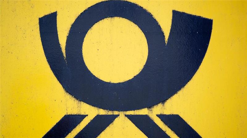 Blick auf einen Briefkasten der Deutschen Post, auf dem das Posthorn-Logo zu sehen ist.