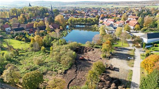 Blick aus der Vogelperspektive auf Lutters Mühlenteich: Im Vordergrund ist die abgebaggerte Biotopfläche zu sehen, auf der einmal ein Spielplatz entstehen soll.