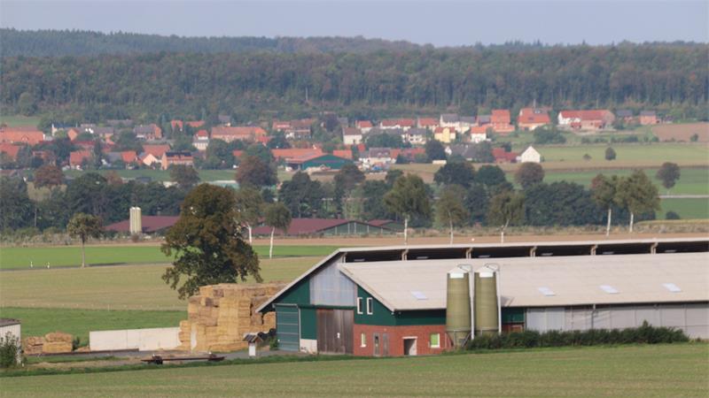 Blick über eine Landschaft mit landwirtschaftlich genutzten Ställen.