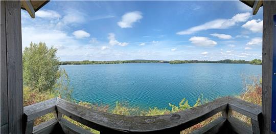 Blick vom Vogelbeobachtungsturm auf den Kiesteich. Die Panoramafunktion der Kamera lässt den geraden Balken im Vordergrund geschwungen erscheinen – die gute Wasserqualität lässt sich allerdings nur erahnen. Fotos: Gereke, dpa, Fischereiverein