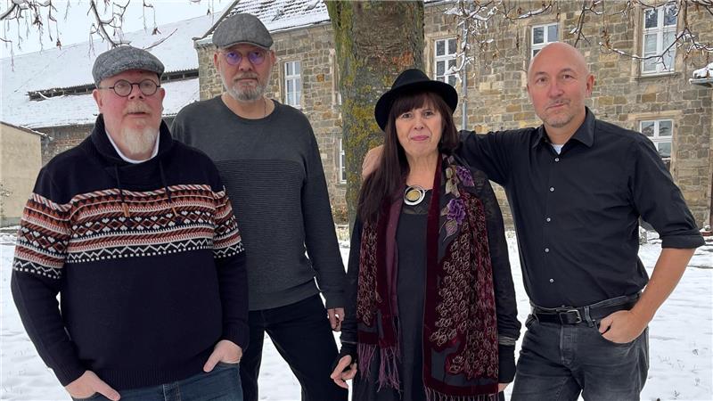 Drei Männer und eine Frau stehen vor einem Baum in winterlicher Atmosphäre.