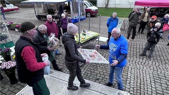 „Blumen-Rudi“ Hoffmeister (l.) und die übrigen Marktbeschicker verabschieden Carsten Nolte (im blauen Shirt) mit Geschenken und warmen Worten.