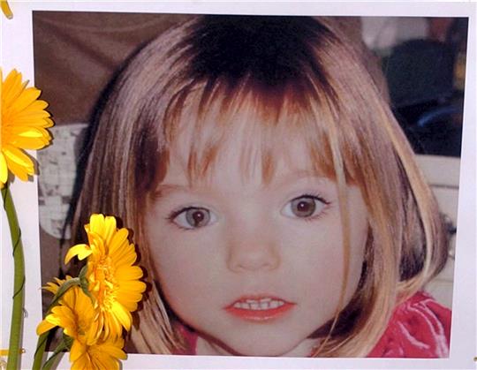 Blumen stehen vor einem Bild, das die verschwundenen Madeleine McCann (Maddie) auf einem Foto zeigt, das ihre Eltern im Zusammenhang mit dem Verschwinden des Kindes veröffentlich haben. Foto: Luis Forra/LUSA FILE/dpa