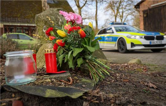 Blumen und Kerzen stehen vor einem Haus in Westervesede in der Gemeinde Scheeßel, in dem ein Mann zwei Personen erschossen haben soll.