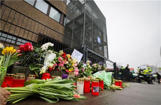 Blumen und Kerzen vor dem Eingangsbereich eines Gemeindehauses der Zeugen Jehovas. Nach der Amoktat in den Räumen der Zeugen Jehovas in Hamburg dauern die Ermittlungen weiter an.