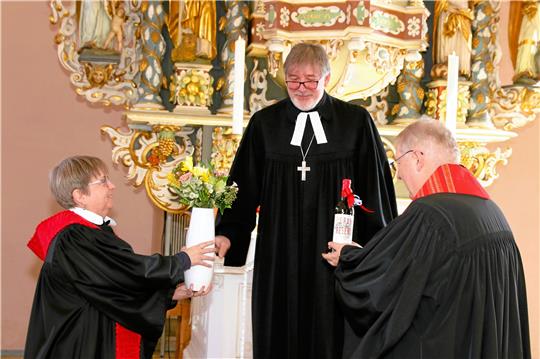 Blumen und Wein überreicht Propst Thomas Gunkel (M.) zum Abschied an Sabine und Joachim Prunzel in der St.-Andreas-Kirche. Foto: Leifeld