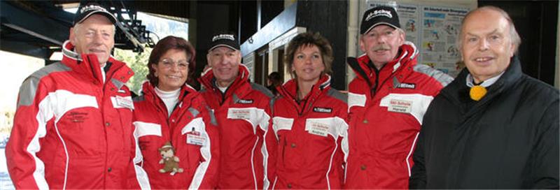 Hahnenklee rettet sich 2006 aus eigener Kraft und mit Goslarer Hilfe Fünf Personen in roten Jacken mit weißen Streifen und eine Person in dunklem Anzug stehen nebeneinander in Innenraum.