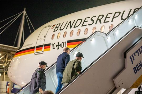 Bodyguards bringen Bundeskanzler Olaf Scholz (SPD, M) nach einem Luftalarm am Ende seines Solidaritätsbesuches in Israel in sein Flugzeug.