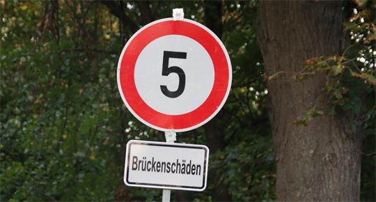 Ein Verkehrsschild mit dem Zusatz "Brückenschäden" zeigt die Höchstgeschwindigkeit 5 km/h an.