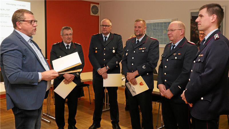 Bevölkerungsschutz: Wofür Liebenburg jetzt mehr Geld ausgibt Sechs Personen stehen in einer Reihe, vier haben Urkunden in der Hand, fünf tragen Feuerwehr-Uniformen.